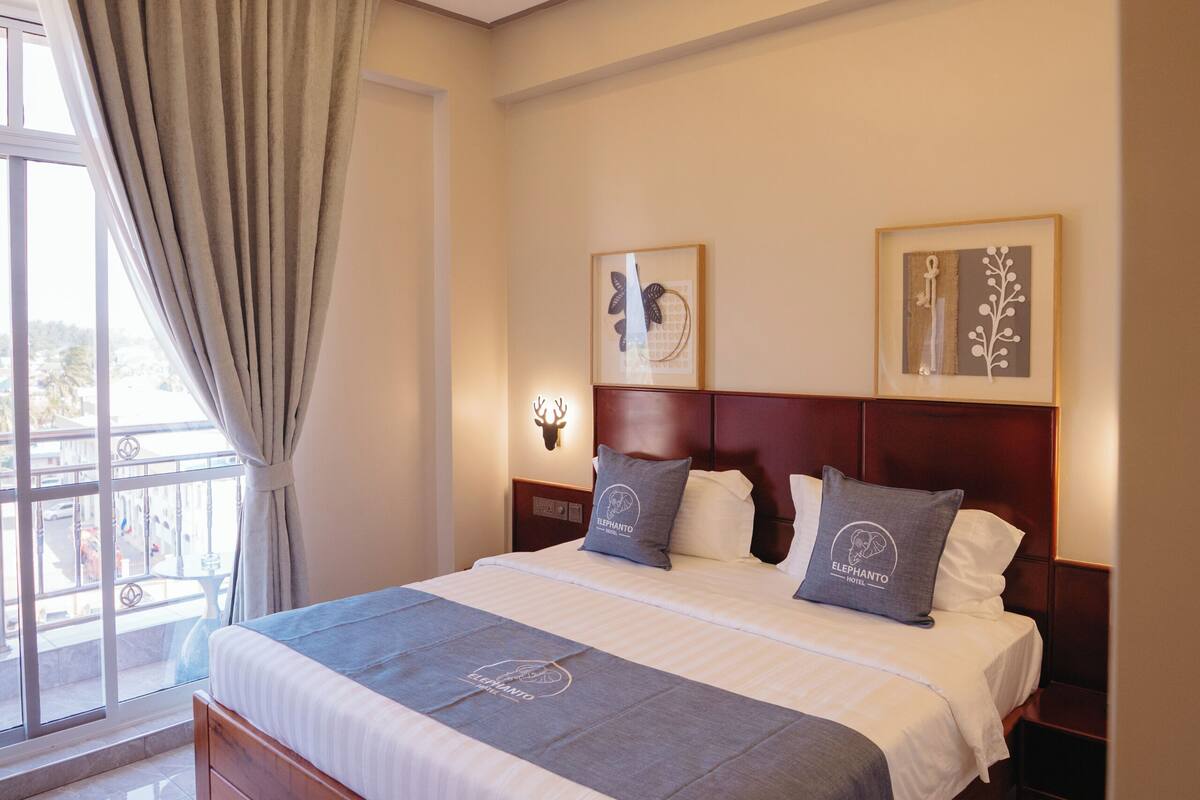 Una habitación de hotel moderna con una cama grande, ventilador de techo y obras de arte en las paredes.