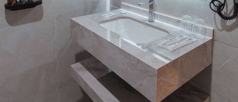 Un baño moderno con un espejo grande, un lavabo y un secador de pelo en la pared.