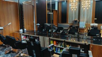 A salon with multiple black salon chairs, a large mirror, and shelves with various hair products.