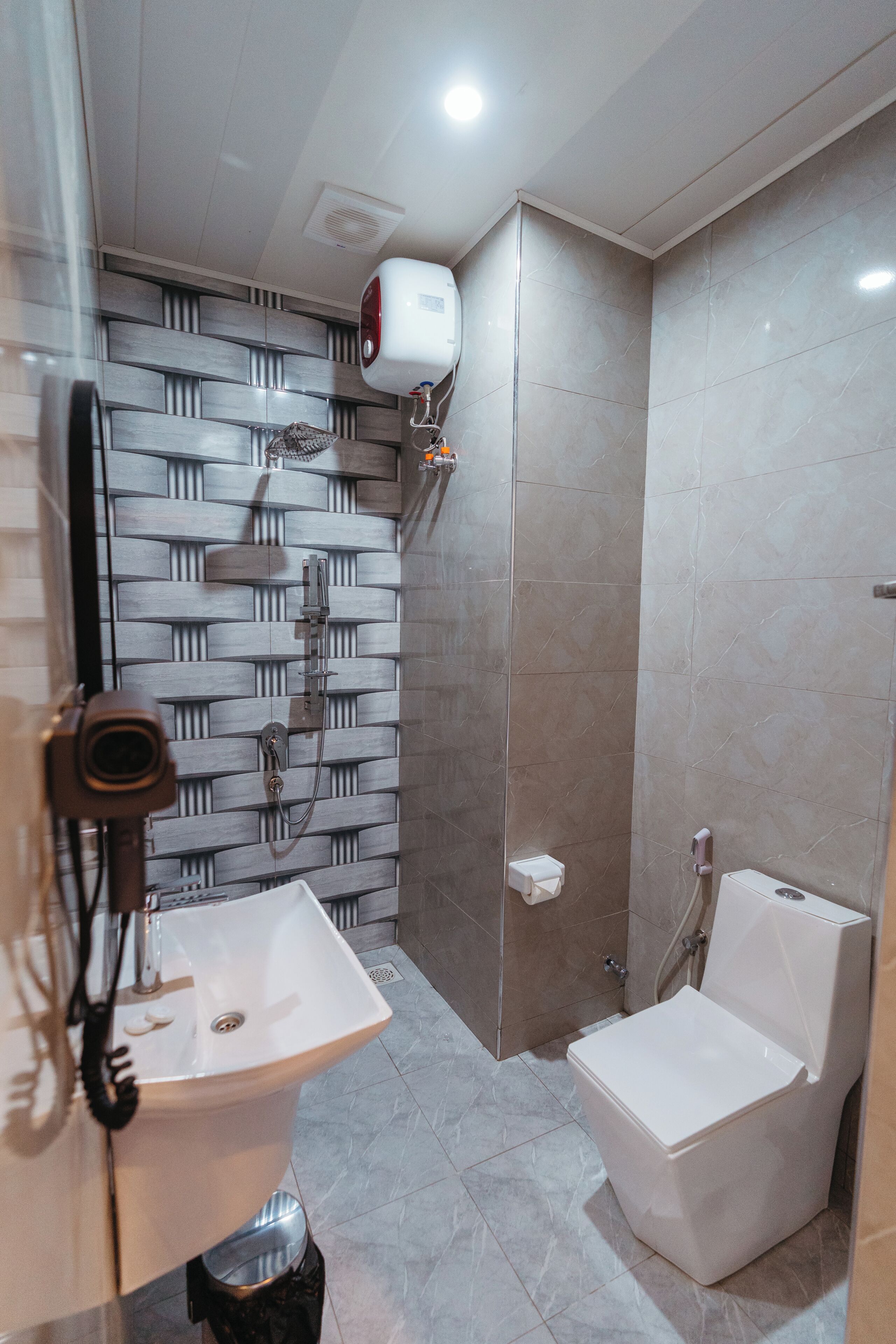 A modern bathroom with a shower, toilet, and sink.