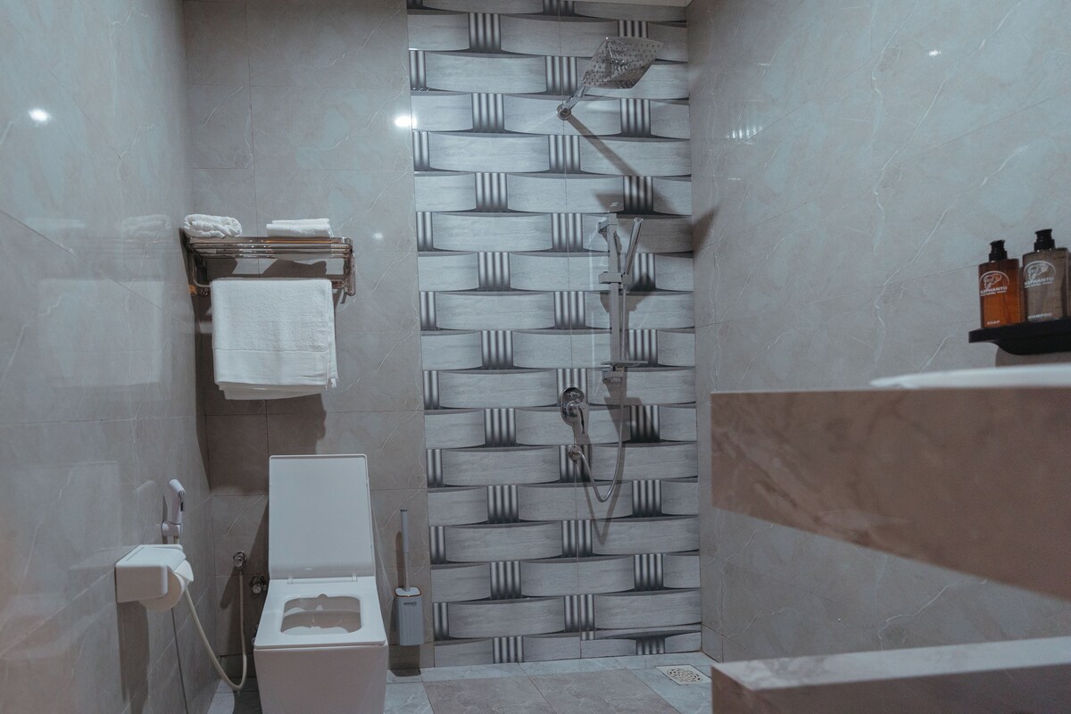 A bathroom with a shower, toilet, and towel rack.