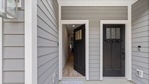 A house entrance with a dark door and a light-colored exterior.