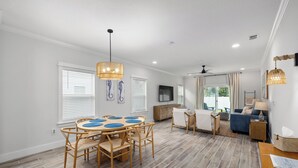 A spacious living area with a dining table, chairs, a sofa, and a TV.