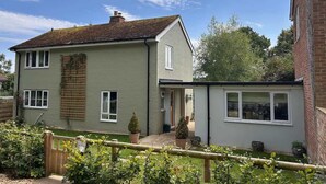 Une maison à deux étages avec un jardin, une clôture en bois et un mur en briques.