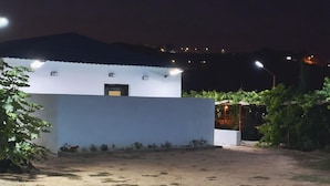 A building with a flat roof and a white facade, surrounded by a dirt area with sparse vegetation. - Al-Mutawa Residential Countryside Resort (Al Mandaq)