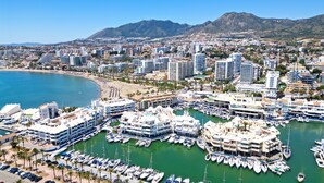Una marina con barche ormeggiate, una spiaggia e edifici sullo sfondo.