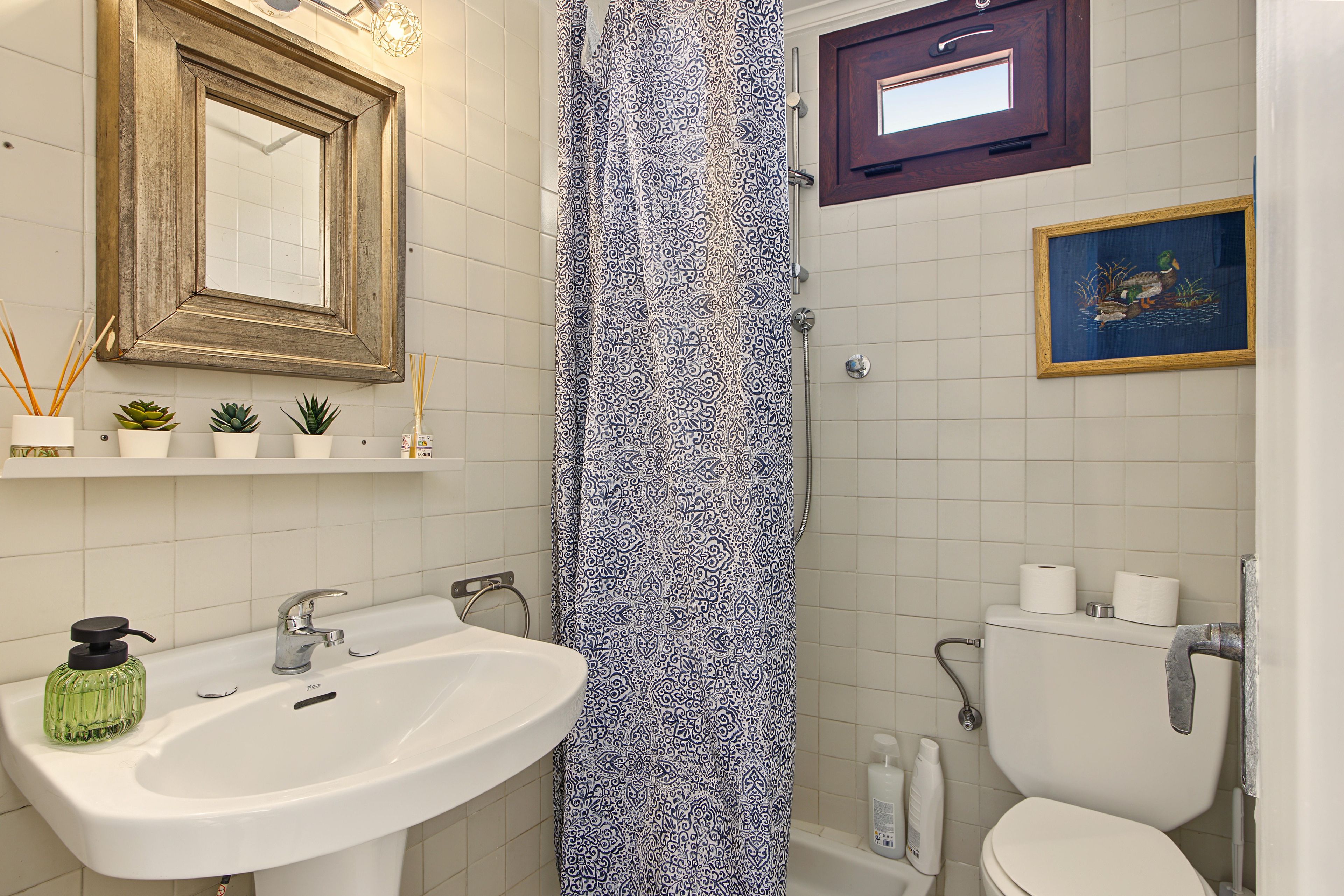 Un baño con lavamanos, inodoro, ducha y espejo.