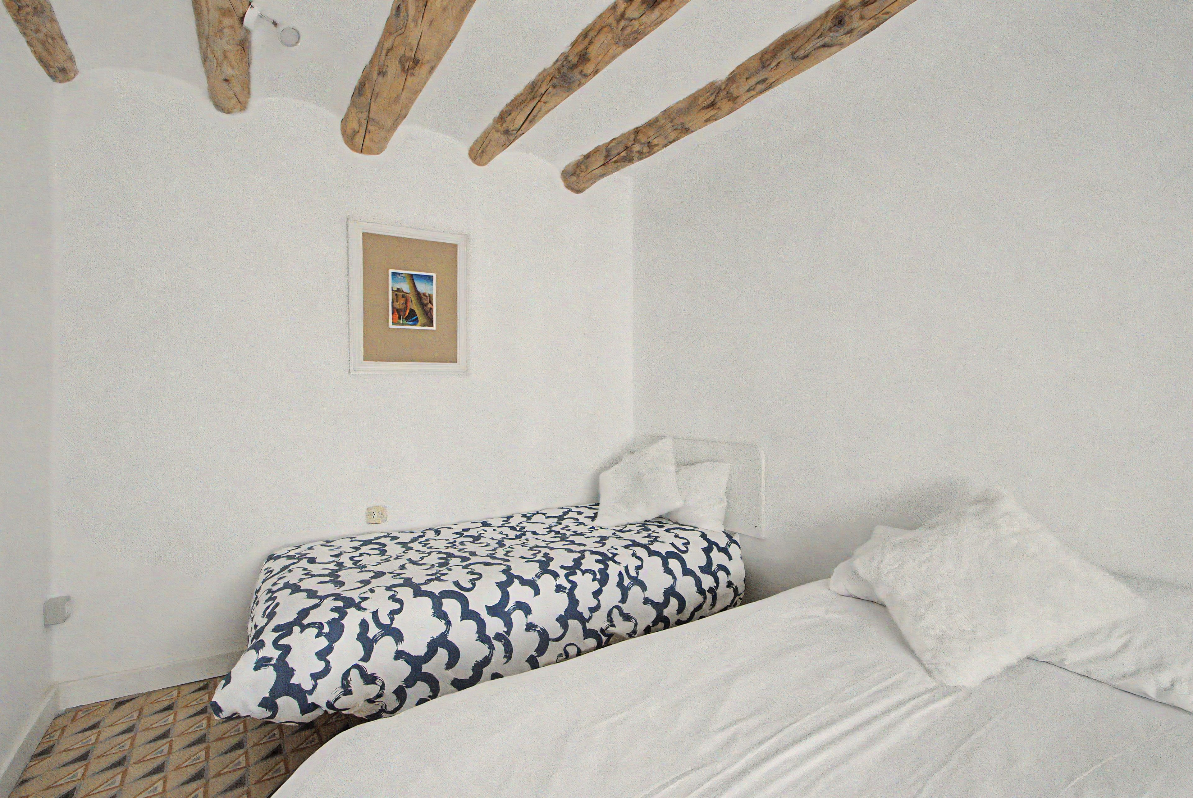 Un dormitorio con cama, almohada, un cuadro colgado en la pared y una viga de techo de madera.