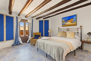 A hotel room with a bed, a chair, a desk, and a painting on the wall. - Country House 'Medina' with Private Pool, Private Terrace and Wi-Fi (Agón)