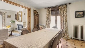 Un comedor con una mesa larga, sillas, una chimenea y una ventana con cortinas.