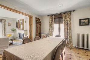 A dining area with a long table, chairs, a fireplace, and a window with curtains. - Country House 'Medina' with Private Pool, Private Terrace and Wi-Fi (Agón)
