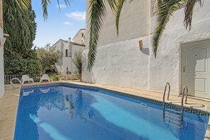 A swimming pool with a clear blue water surface, surrounded by a white wall and palm trees. - Country House 'Medina' with Private Pool, Private Terrace and Wi-Fi (Agón)