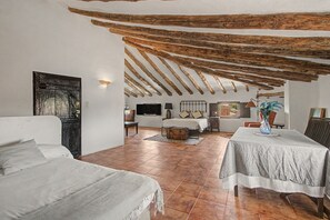 A spacious room with a high ceiling, exposed wooden beams, a bed, a table, and a chair. - Country House 'Medina' with Private Pool, Private Terrace and Wi-Fi (Agón)