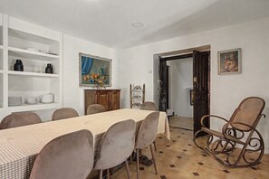 Uma sala de jantar com uma mesa posta para seis pessoas, cercada por cadeiras, um armário de madeira e um quadro na parede.