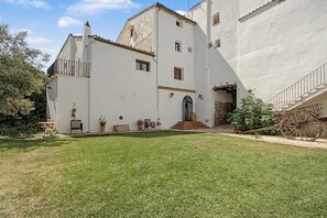 A white building with a central entrance, a small porch with a bench, and a large wheelbarrow to the right. - Country House 'Medina' with Private Pool, Private Terrace and Wi-Fi (Agón)