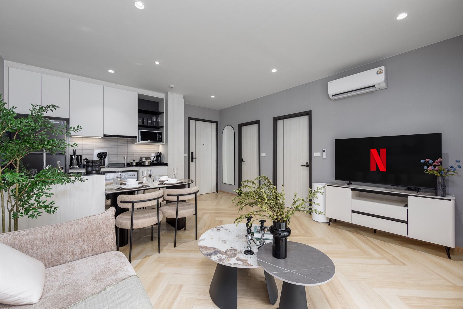 A modern living space with a kitchen, dining area, and a TV displaying the Netflix logo.