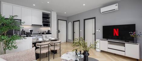 A modern living space with a kitchen, dining area, and a TV displaying the Netflix logo.