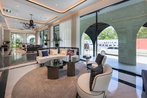A modern lobby with a curved sofa, a coffee table, and a seating area with a view of the street. - The Title Legendary BangTao by TropicLook (Choeng Thale)