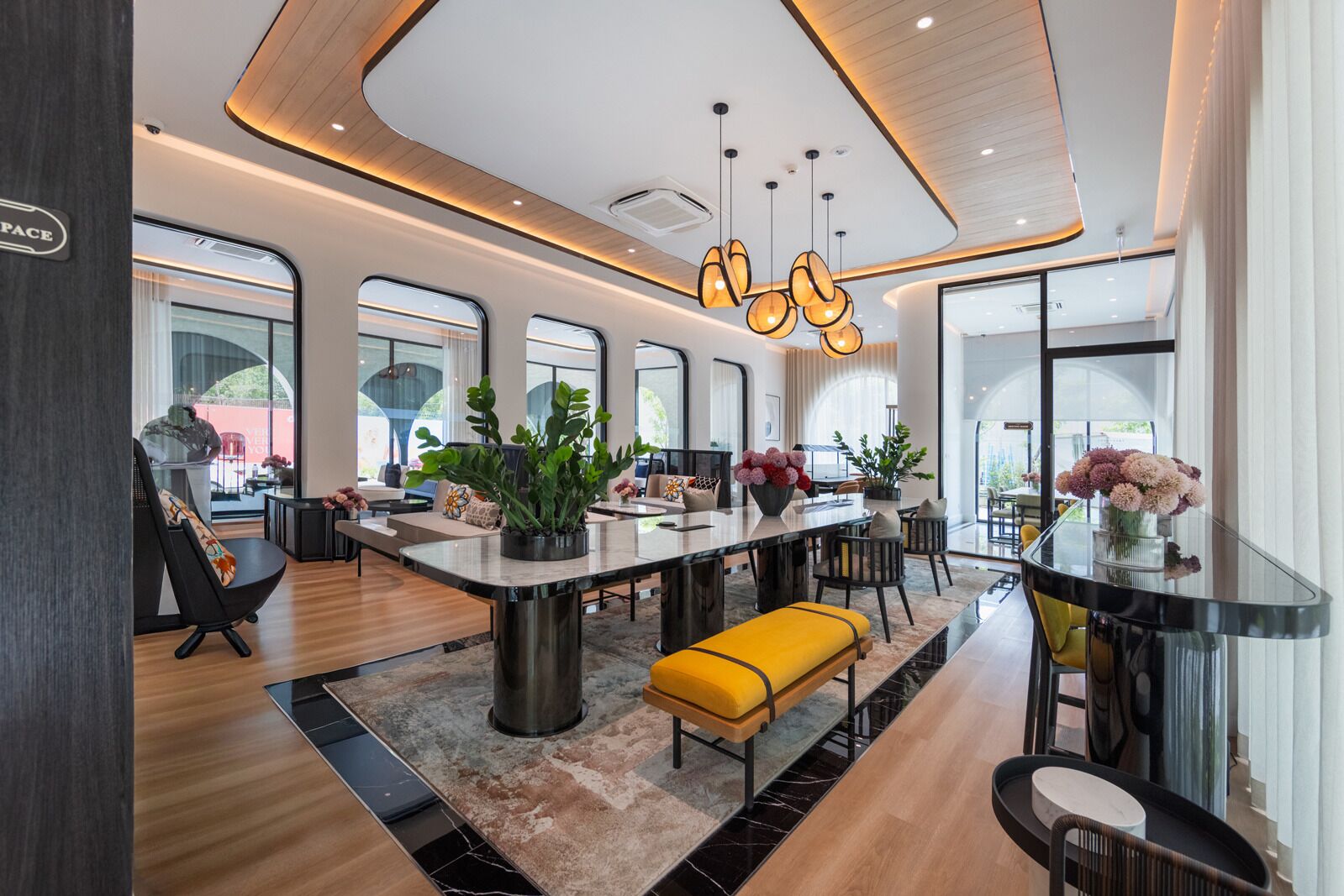 A modern interior with a central island, seating, and large windows.