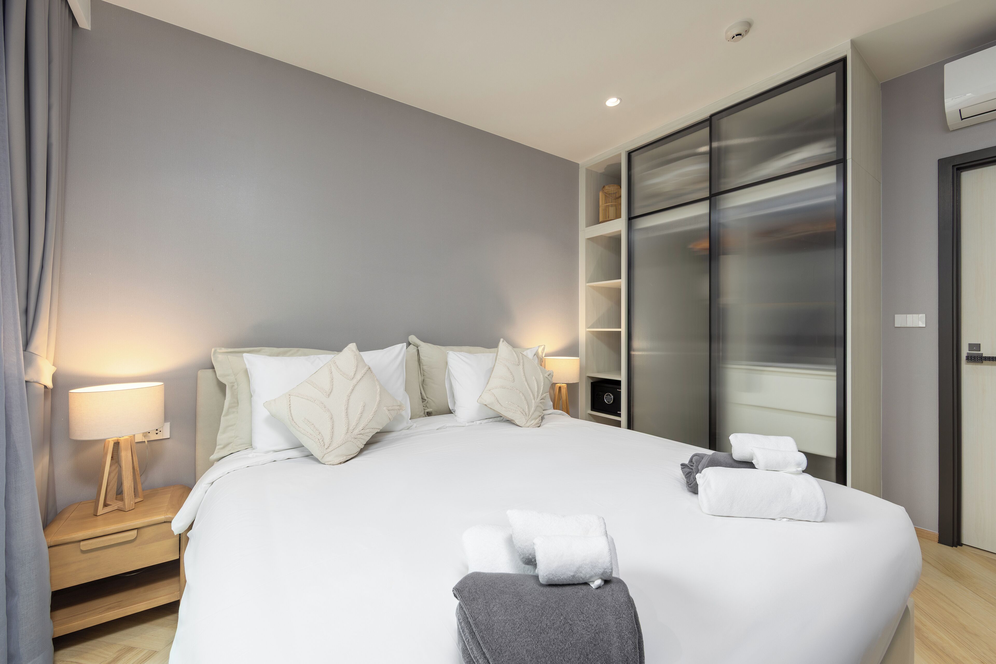 Une chambre d’hôtel moderne dotée d’un grand lit, de lampes de chevet, d’une armoire et d’un téléviseur à écran plat.