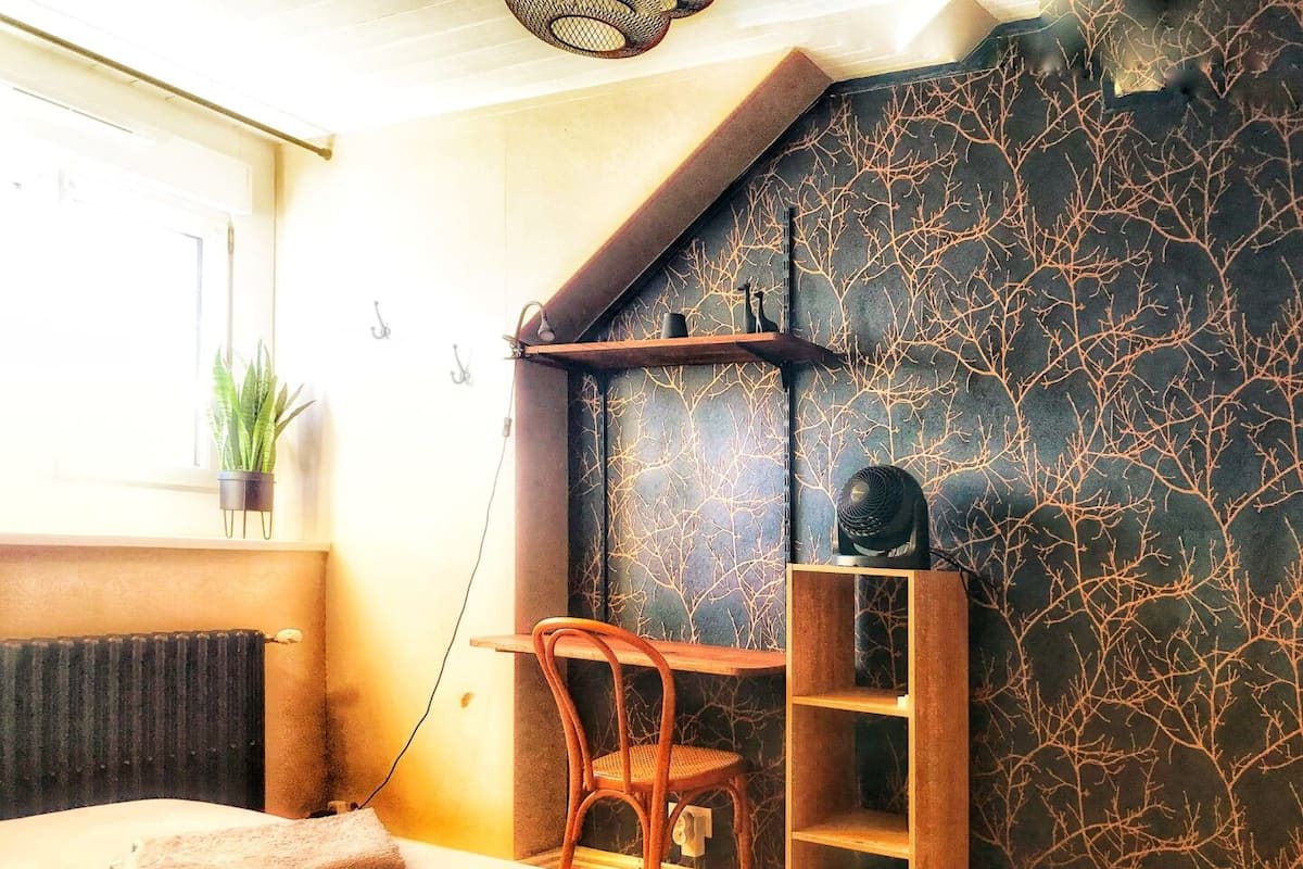 A bedroom with a bed, a chair, a desk, and a radiator.