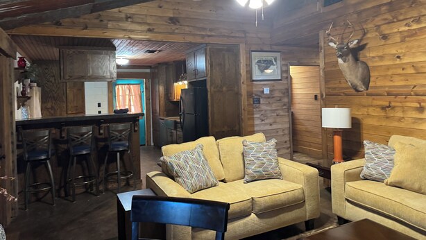 A rustic cabin interior with a wooden ceiling, a ceiling fan, a bar area, and a seating area with two couches and a coffee table. - 
Dularge Fishing Hideaway!
Family and Pet friendly (Houma)