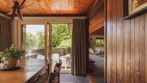 Un interior de madera con comedor, ventanas amplias y vistas al exterior.