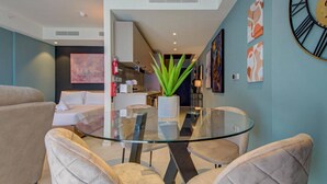 A modern living room with a glass dining table, beige sofas, and a potted plant. - The Official Mercury Suite With Pool & Strong WIFI (St. Julian`s)