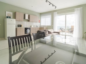 A modern apartment with a dining area, kitchen, and a balcony with a view.