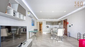 Um apartamento moderno com sala de estar, cozinha, espaço para refeições e uma varanda pequena.