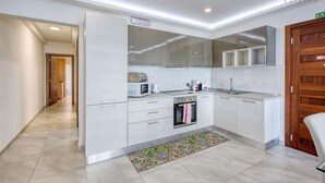 Cozinha moderna com armários brancos, forno embutido e micro-ondas.