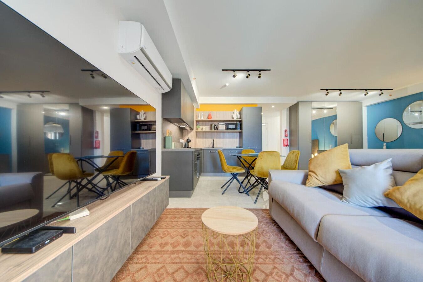 A modern living room with a sofa, a coffee table, and a dining area with chairs.