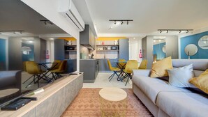 Un salon moderne comprenant un canapé, une table basse et un coin repas avec des chaises.