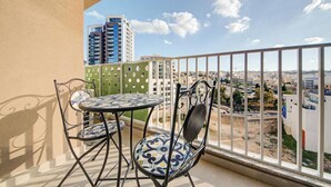 Ein Balkon mit Tisch und Stühlen, der einen Blick auf eine Stadt mit Gebäuden und blauem Himmel bietet.