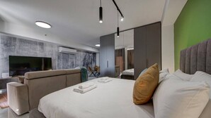 Ein modernes Hotelzimmer mit einem großen Bett, einer Couch, einem Flachbildfernseher und einer Wand in Grünton.