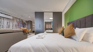 A modern hotel room with a large bed, a sofa, a chair, and a green accent wall. - Modern City Home | Walk to Nightlife & Dining (St. Julian`s)