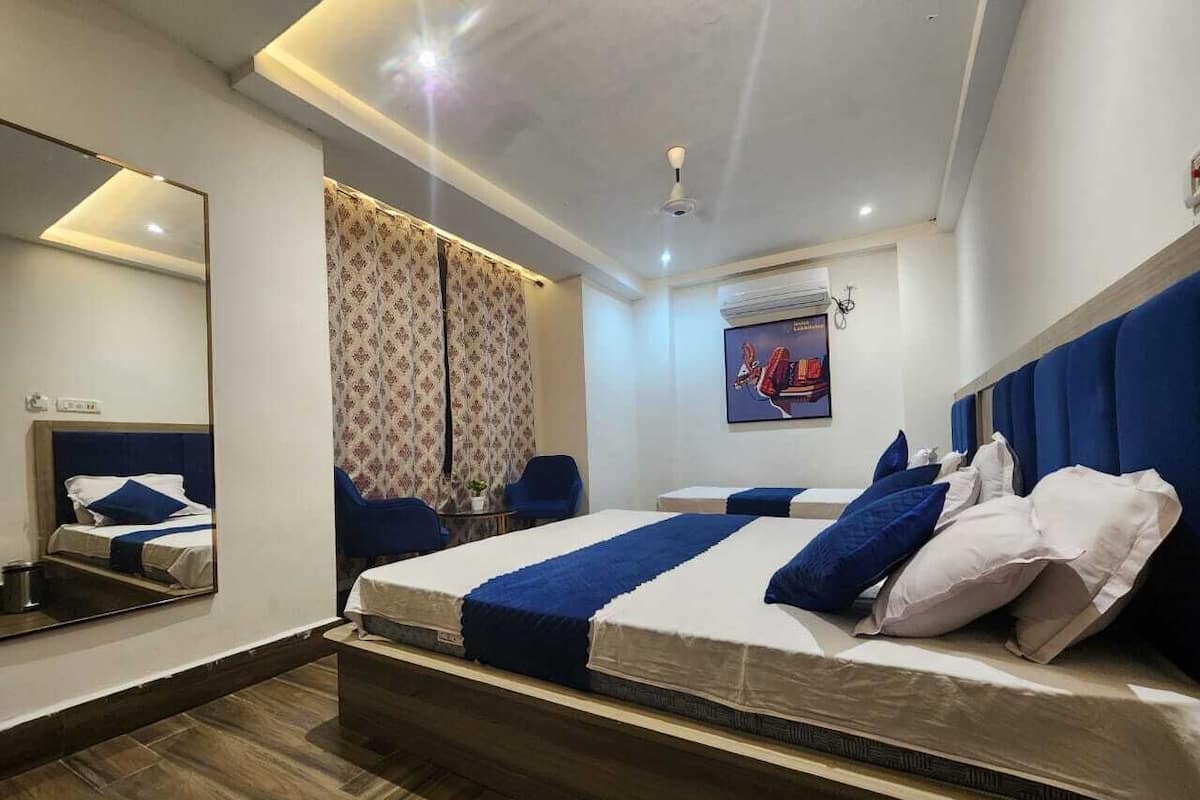 A modern hotel room with a large bed, a desk, a chair, a mirror, and a TV.
