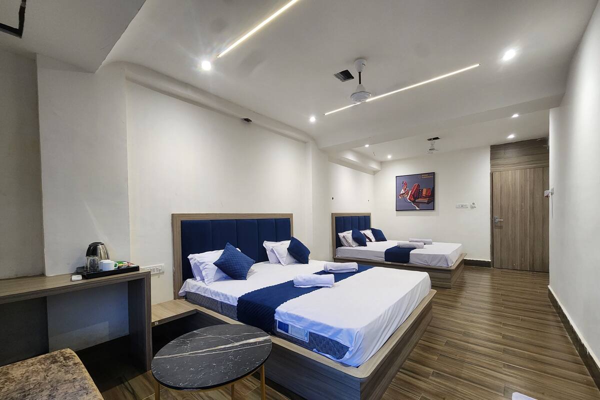 A hotel room with three beds, a desk, and a small table.