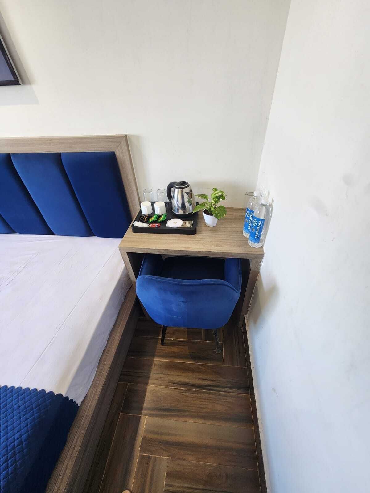 A small hotel room with a bed, a desk with a tray of breakfast items, a coffee maker, and a water bottle.