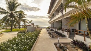 Un resort con un viale alberato da palme, una piscina e un edificio con balconi.