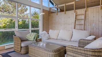 Une pièce chaleureuse avec une grande fenêtre, des meubles en osier et un décor intérieur en bois.