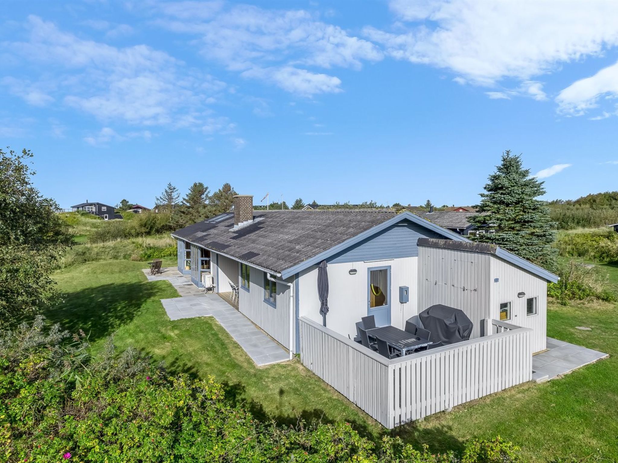 Un b âtiment moderne, de plain-pied, doté d’un patio couvert et entouré d’une pelouse bien entretenue et d’arbres.