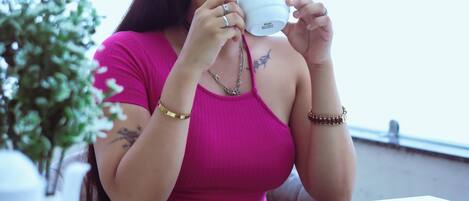 A person seated at a table with a cup, a plate, and a small plant.