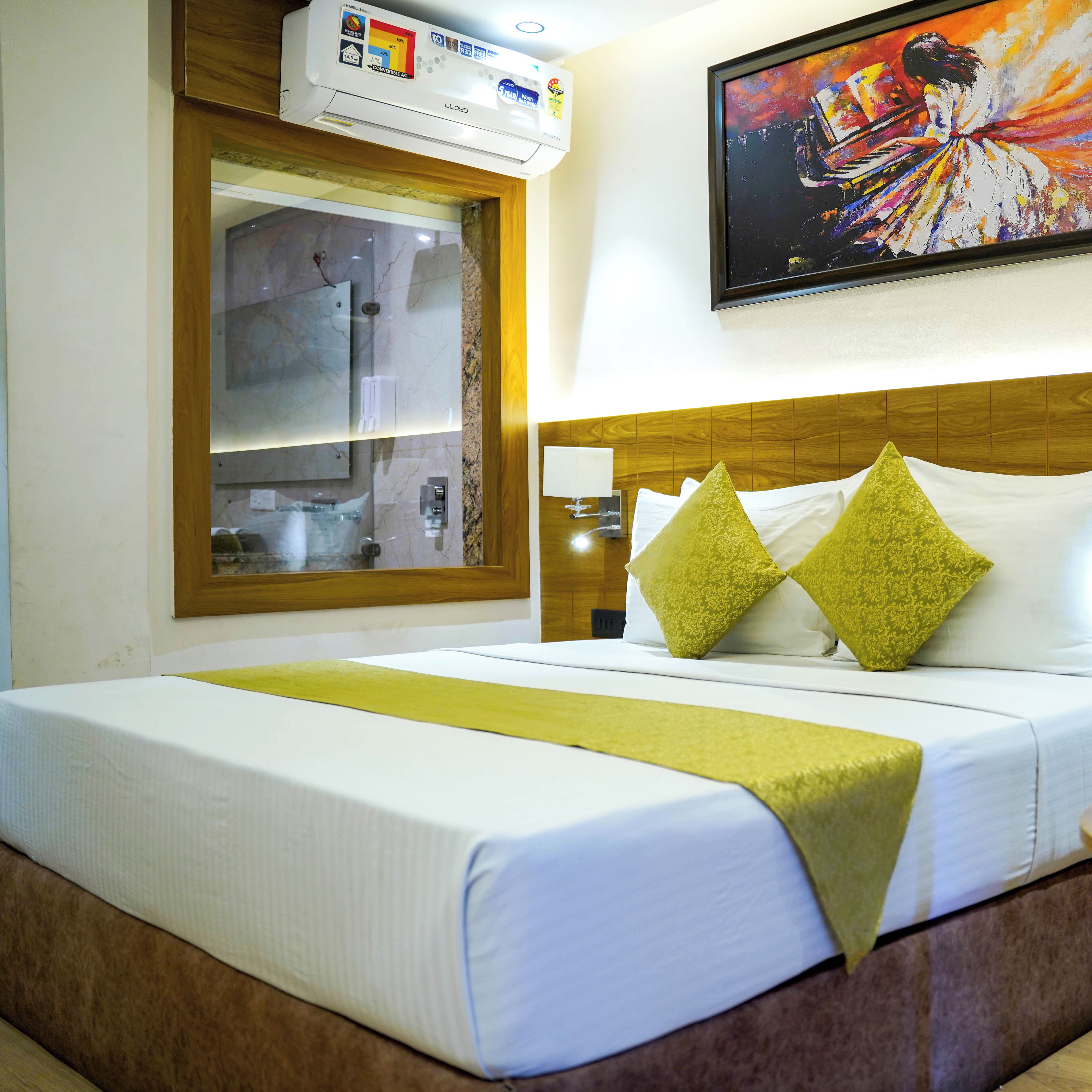 Ein Hotelzimmer mit Bett, Fenster, einem Gemälde und einer Wandklimaanlage.