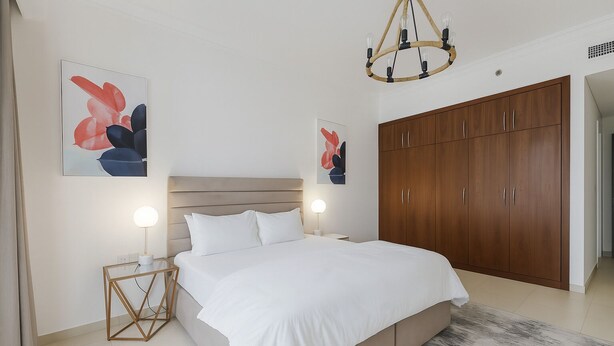 Ein modernes Schlafzimmer mit einem großen Bett, einem Holzschrank und zwei Wandleuchten.