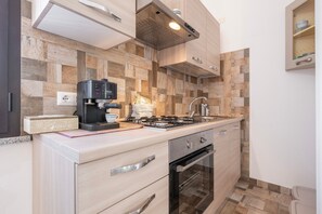 A modern kitchen with a gas stove, oven, and a coffee machine.