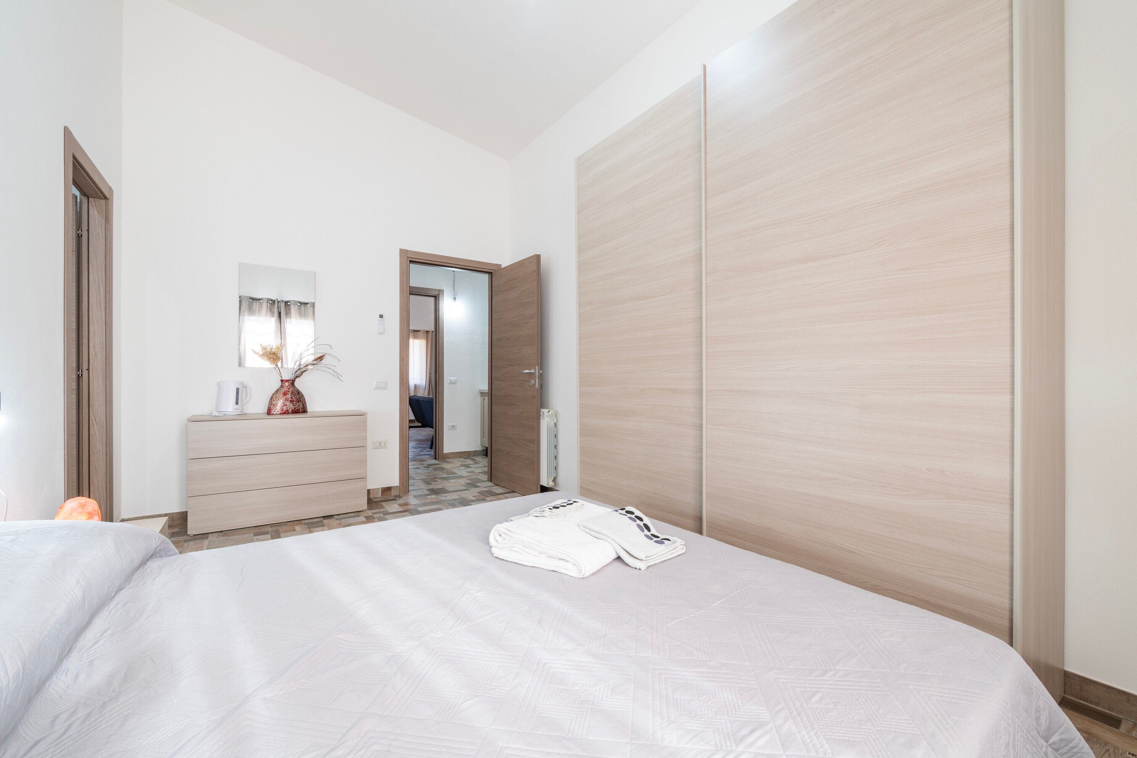 Een hotelkamer met een bed, een dressoir, een spiegel en een kledingkast.