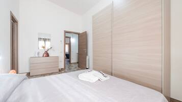 Een hotelkamer met een bed, een dressoir, een spiegel en een kledingkast.