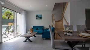Een moderne woonkamer met een bank, een eettafel met stoelen en een trap.