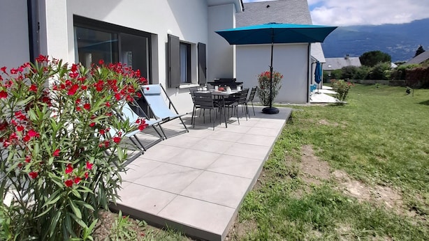 Een modern huis met een patio, een eettafel en stoelen.